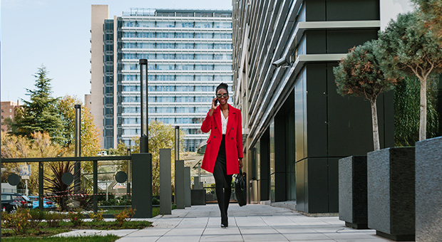 Woman in red jacket talks on the phone on her way to work